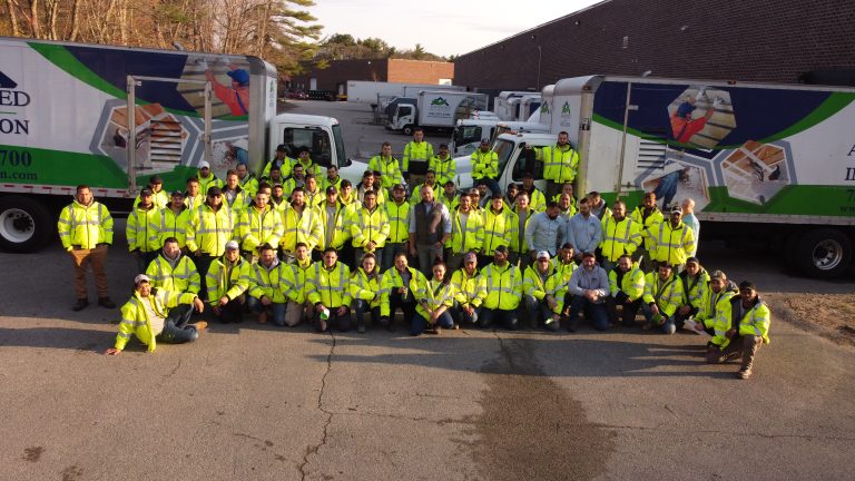 A closeup of the Advanced Green Insulation team posing in front of their vehicles