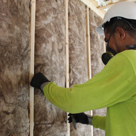 fiberglass2 An Advanced Green worker installs fiberglass insulation on a building wall